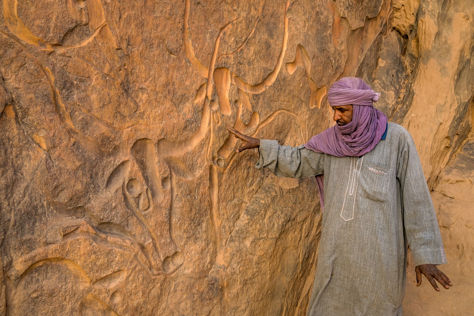 Guide, Abdessalam, pointing out the crying cows rock carving in Tassili National Park