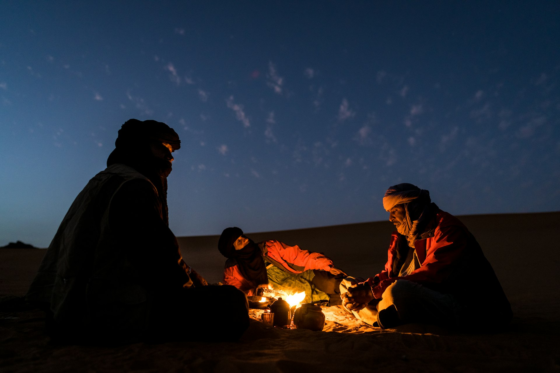 Guides talking over a fire and night sky in Tassili National Park