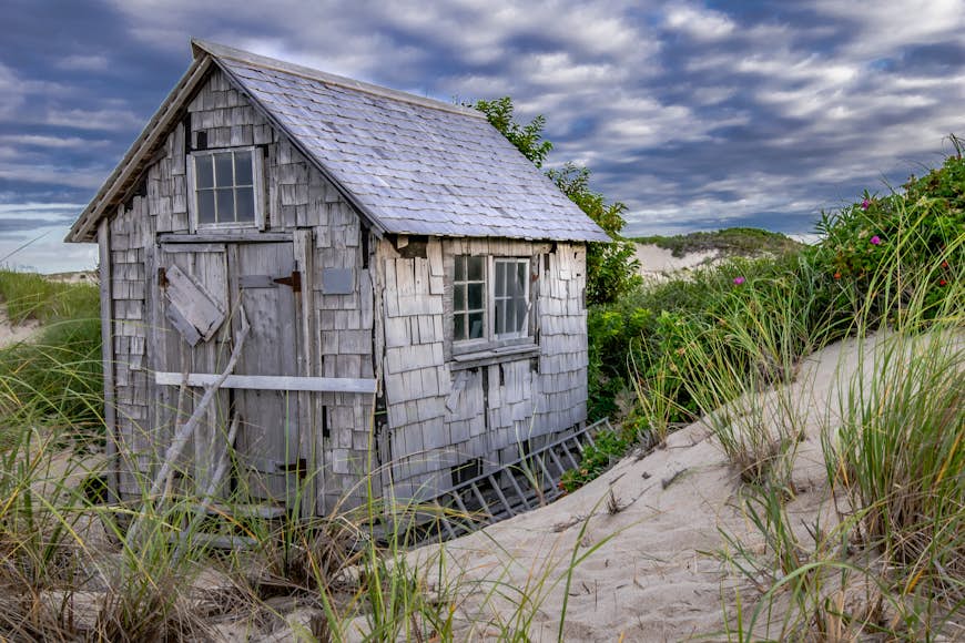 A derelict wooden shack surrounded by sand dunes
