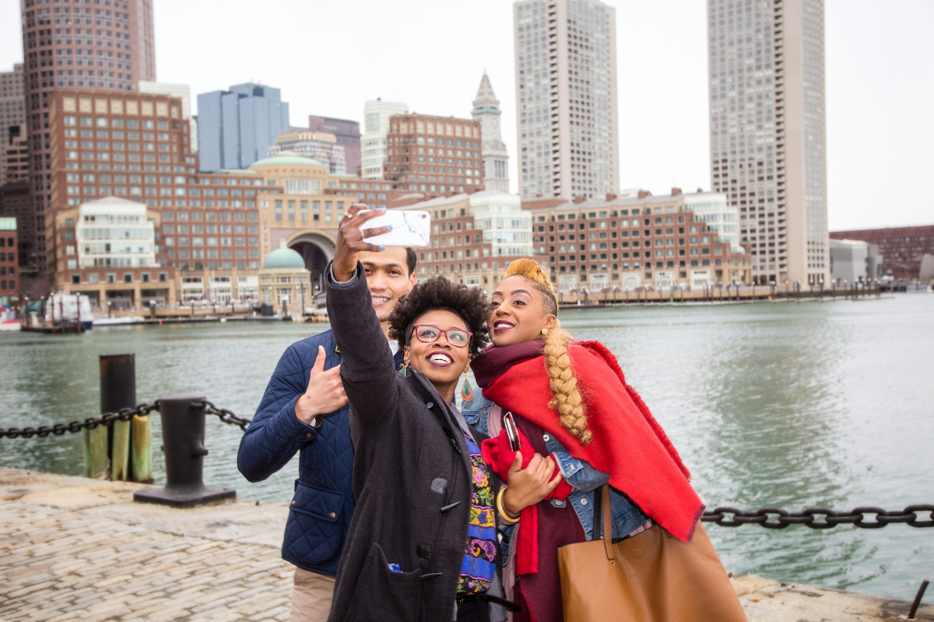 A group of friends take a selfie with Boston Harbor in the background