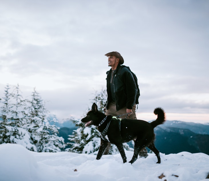 An African American man and his dog hiking in the snow covered mountain areas of Washington state, USA.  An exciting winter adventure.