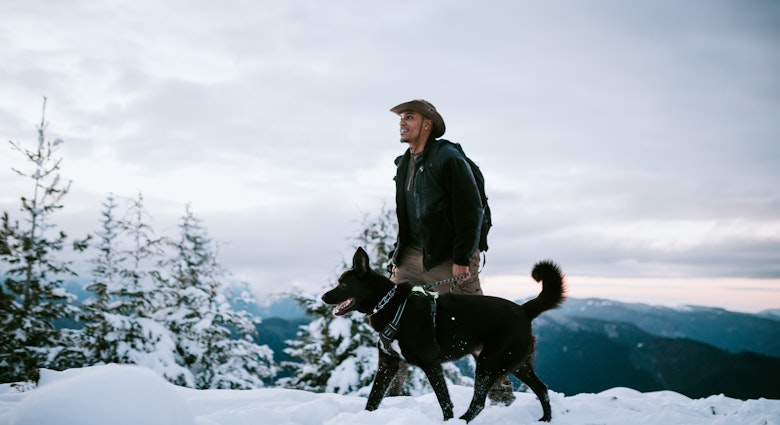 An African American man and his dog hiking in the snow covered mountain areas of Washington state, USA.  An exciting winter adventure.