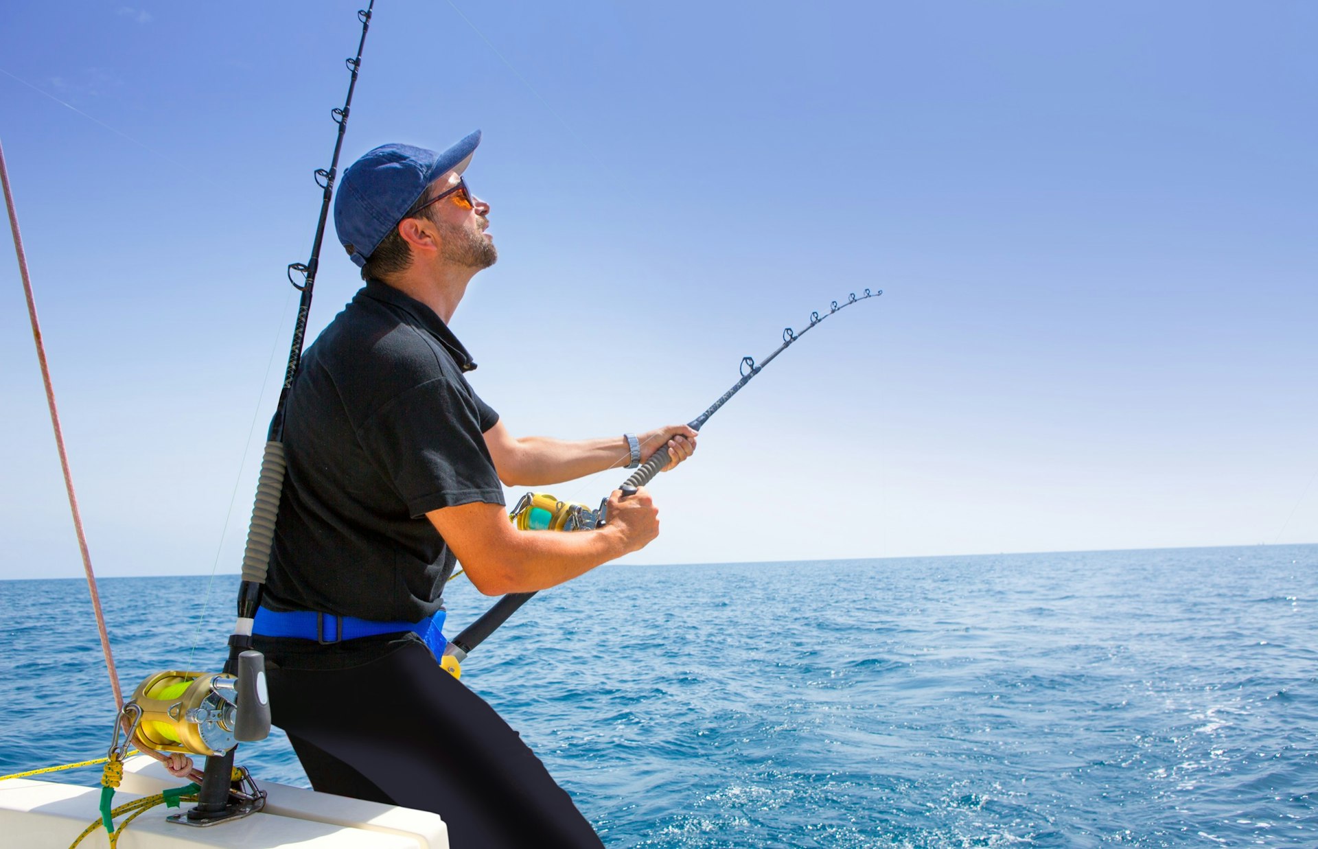Blue,Sea,Offshore,Fishing,Boat,With,Fisherman,Holding,Rod,In