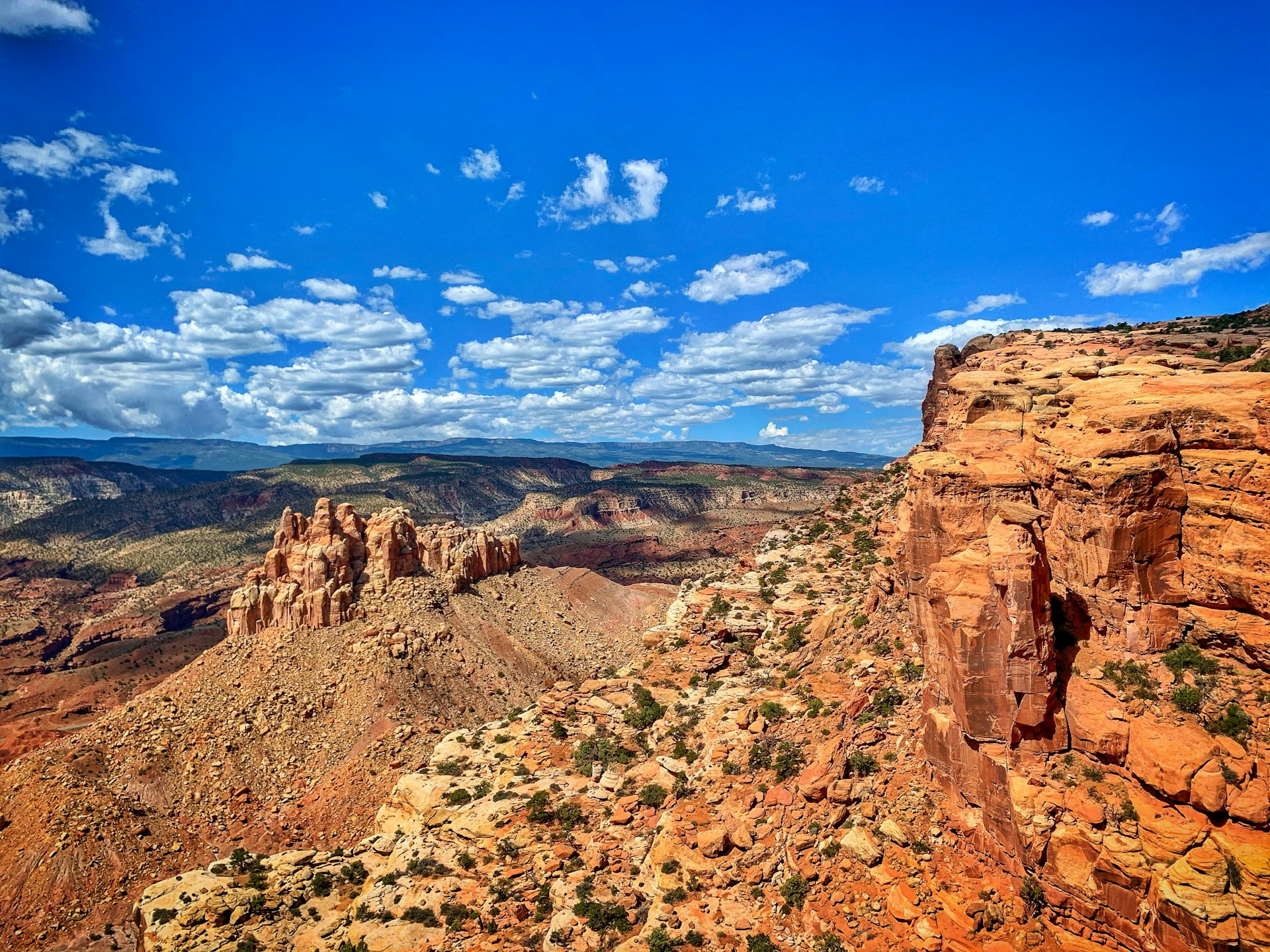 The red-rocked mountainous terrain of Capitol Reef National Park in Utah with cloud-scattered blue sky above