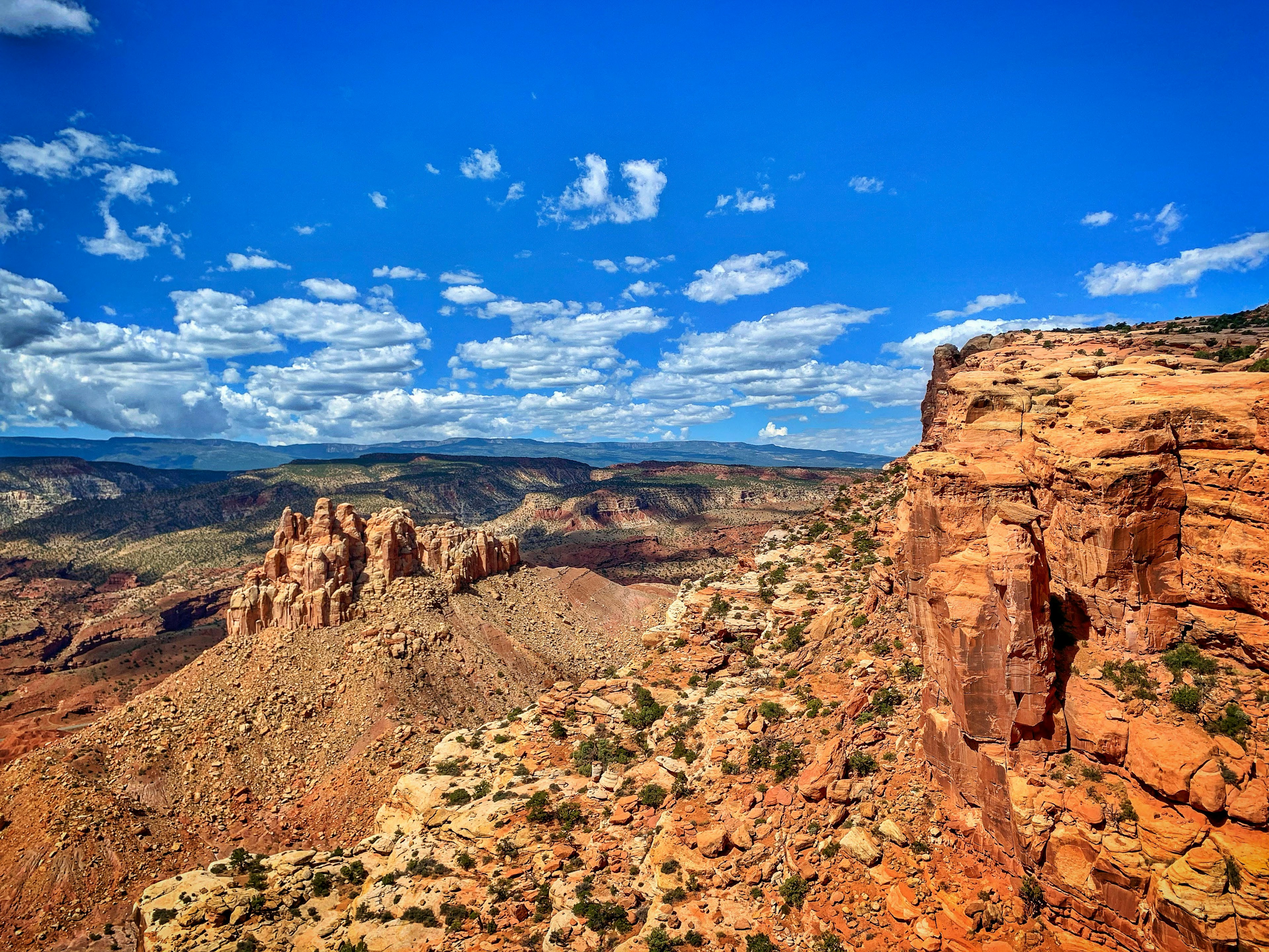 The red-rocked mountainous terrain of Capitol Reef National Park in Utah with cloud-scattered blue sky above