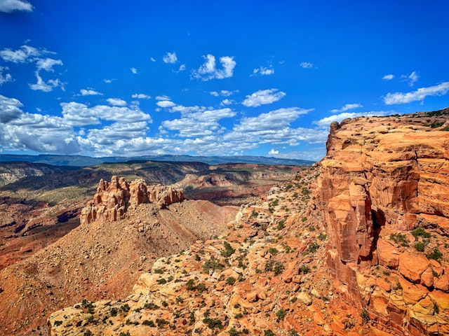 The red-rocked mountainous terrain of Capitol Reef National Park in Utah with cloud-scattered blue sky above