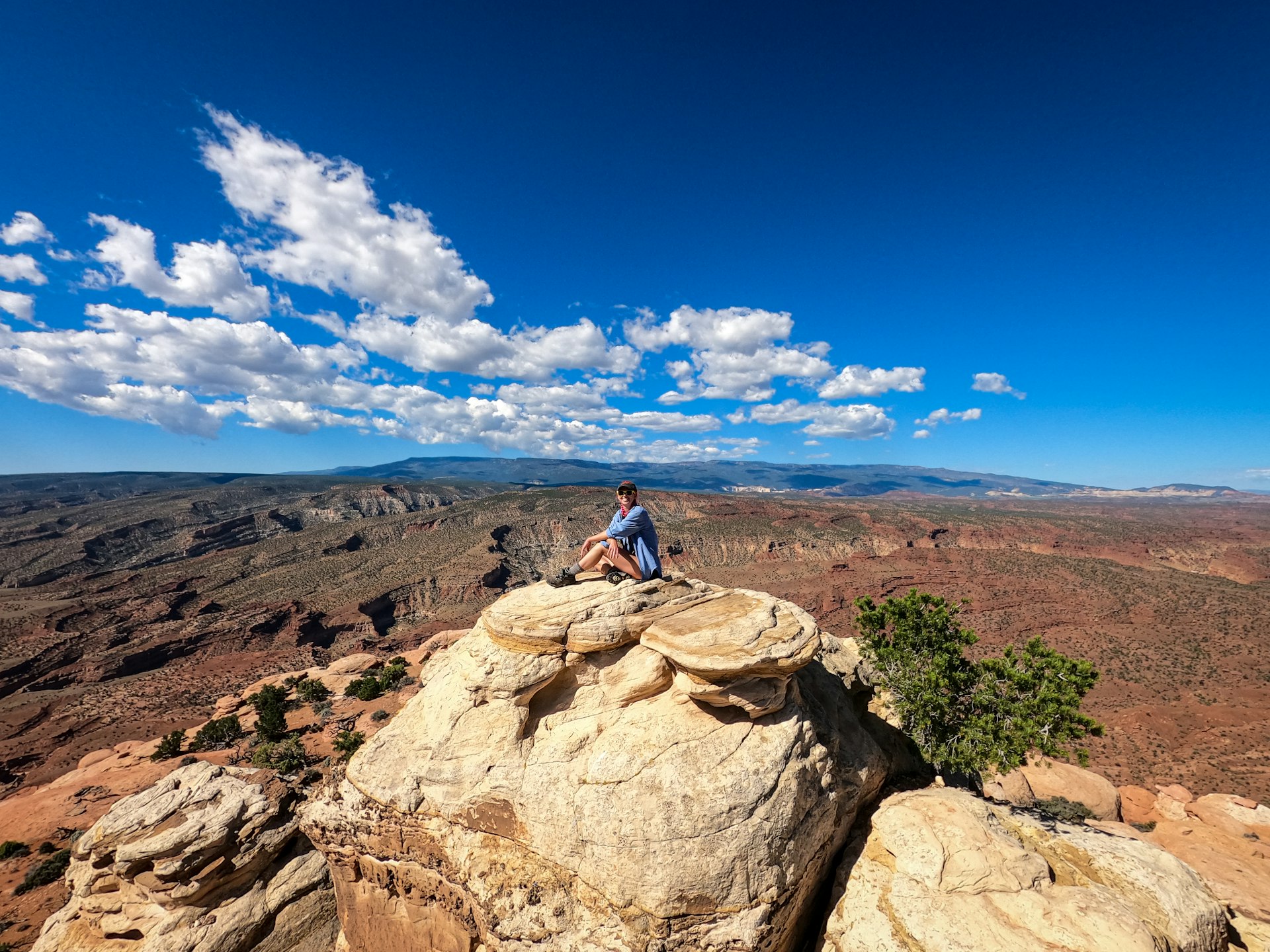 Bailey Freeman sitting on top of a rock formation and smiling to the camera in Capitol Reef National Park, Utah