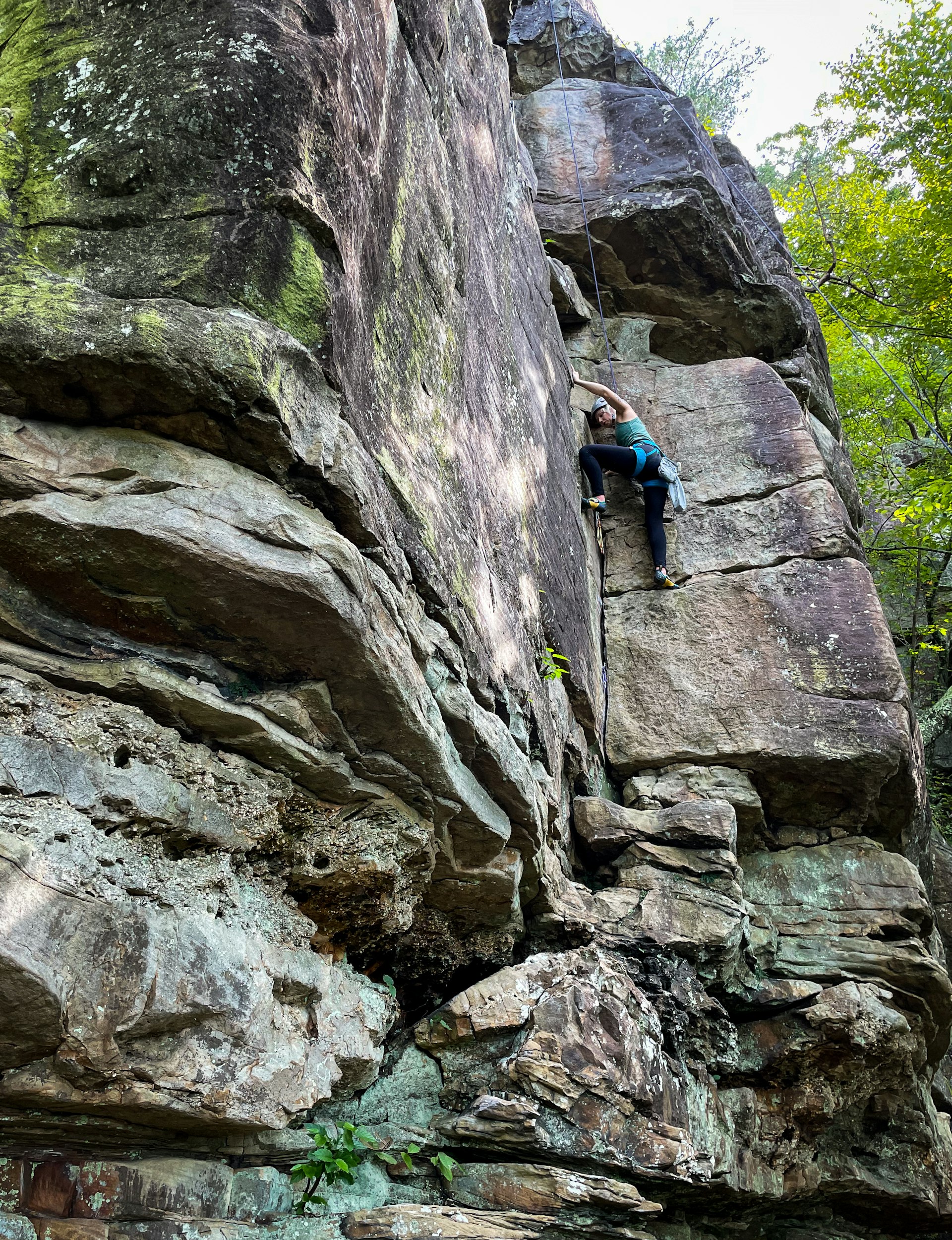 A woman in climbing gear is halfway up a rockface in Chattanooga