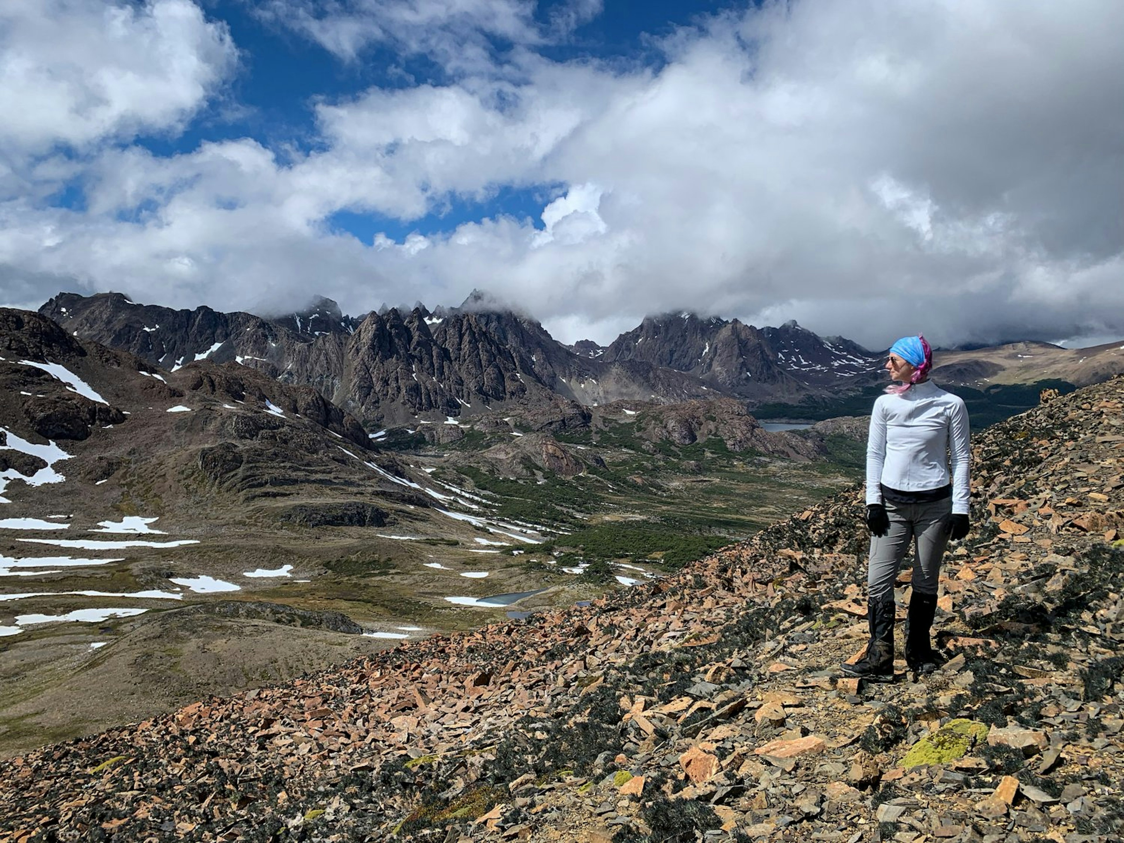 Bailey Freemans stands on a rocky hilltop and gazes out at mountains of Chilean Patagonia