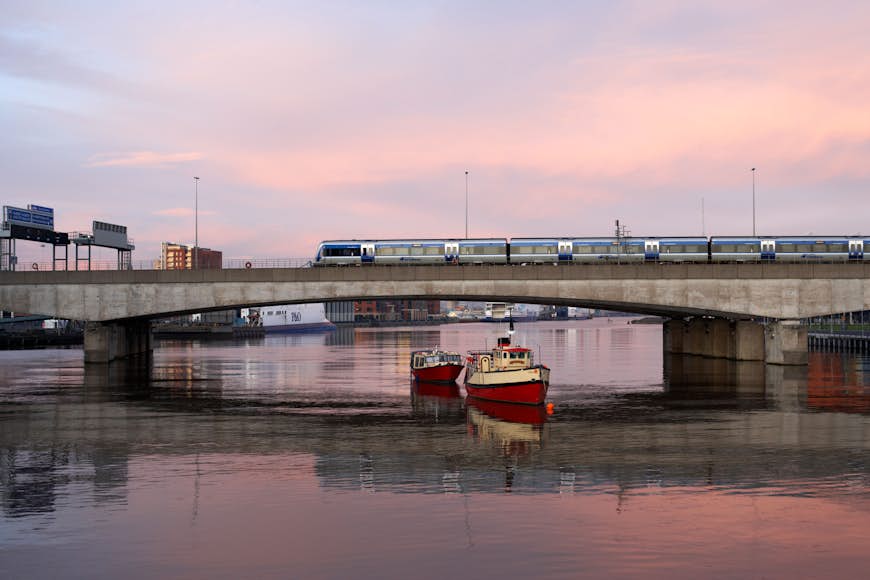 Un train sur un pont traversant une rivière au passage d'un petit bateau