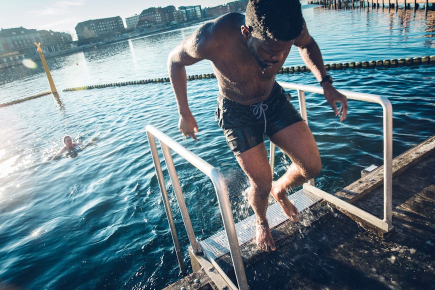 Young man climbing out of Copenhagen harbor after a swim