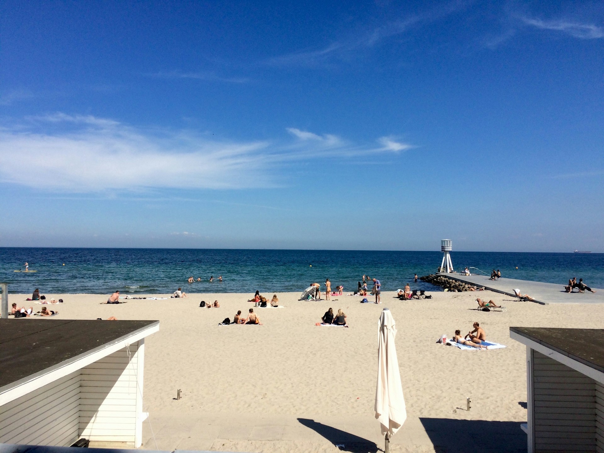 People relaxing on a pristine stretch of white sand with the blue ocean beyond