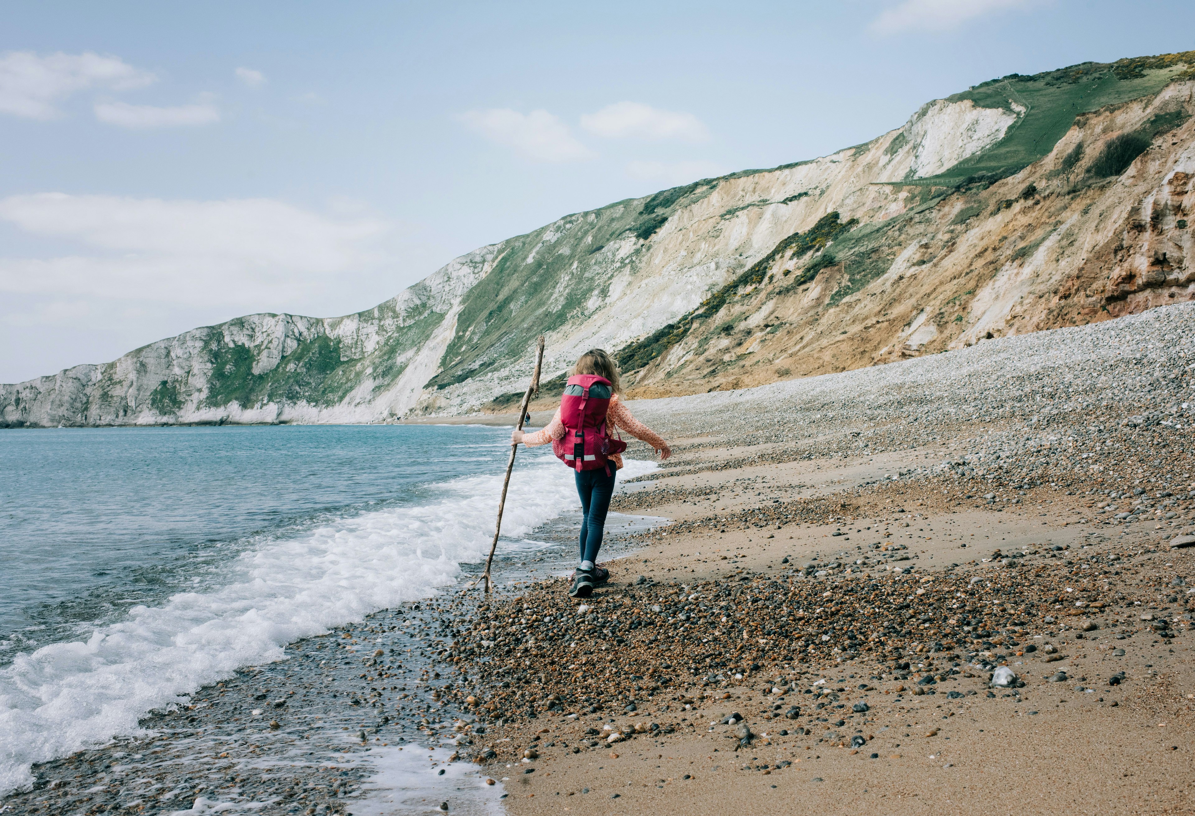 girl walking along the Jurassic coast with a stick on a beautiful day