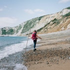 girl walking along the Jurassic coast with a stick on a beautiful day