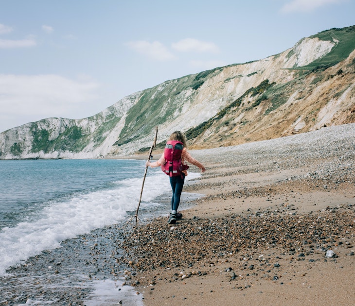 girl walking along the Jurassic coast with a stick on a beautiful day