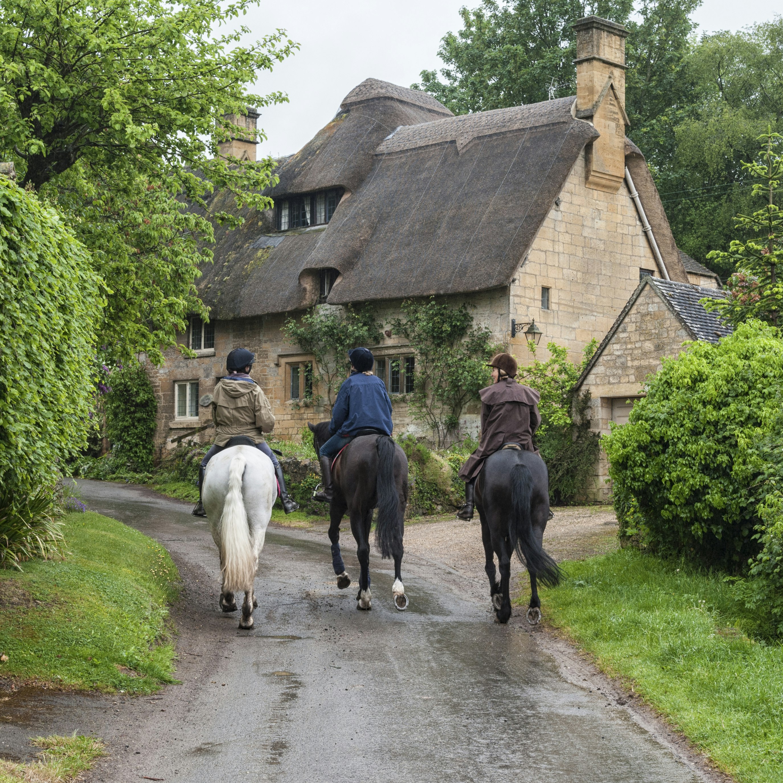 Unidentifed people and horses near cottages in the village of Stanton, Cotswolds district of Gloucestershire.