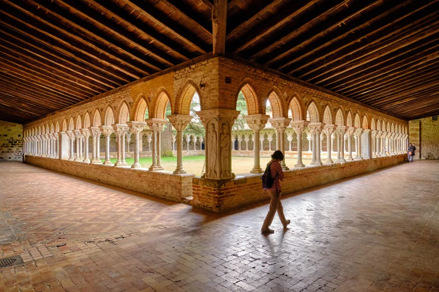 Moissac Abbey monastery courtyard in Moissac with a pilgrim visit. View of the of archways that lines the yard as seen from one corner