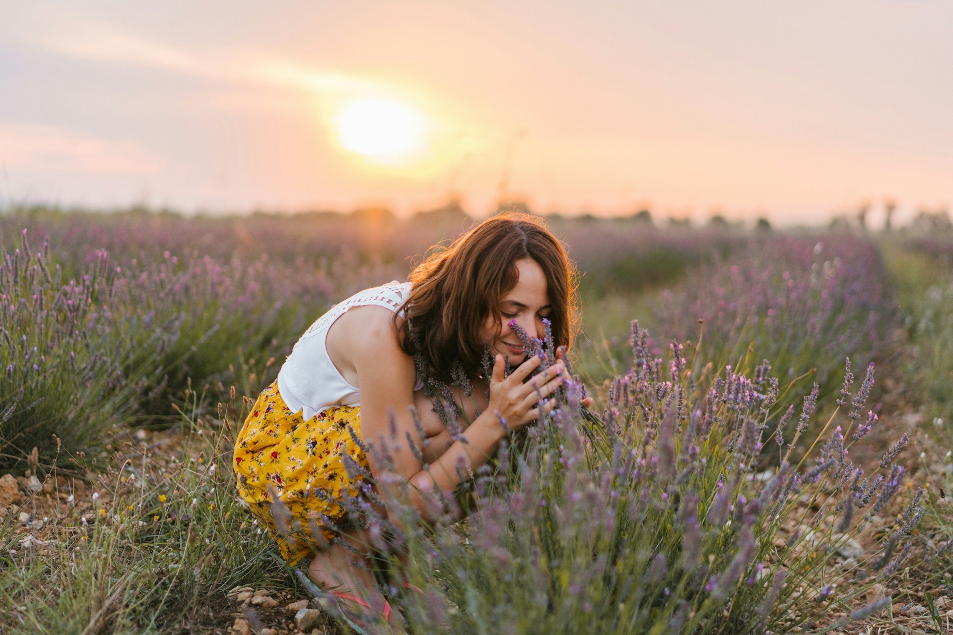 Young Caucasian woman in yellow skirt smelling lavender in a field in Provence, France