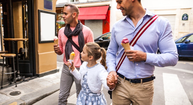 Gay male couple family spending a day outdoor in Paris downtown with young daughter, France.