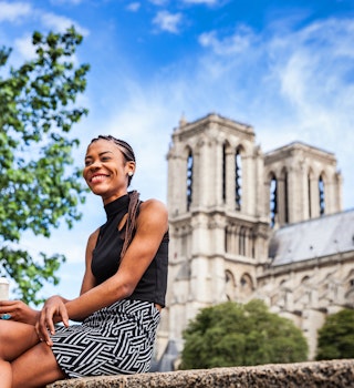 Young black woman walking in Paris near Notre Dame cathedral.