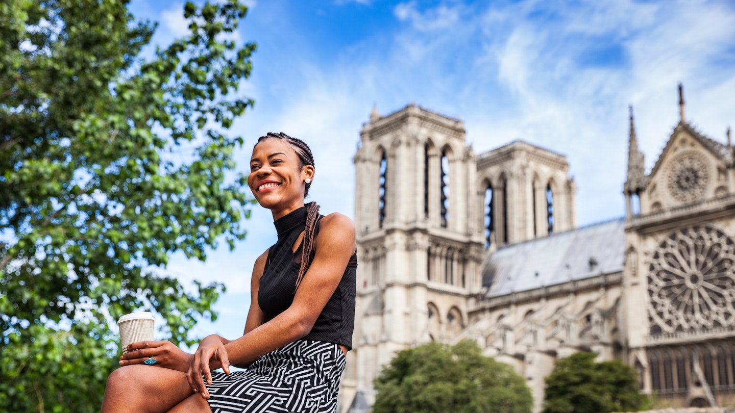 Young black woman walking in Paris near Notre Dame cathedral.