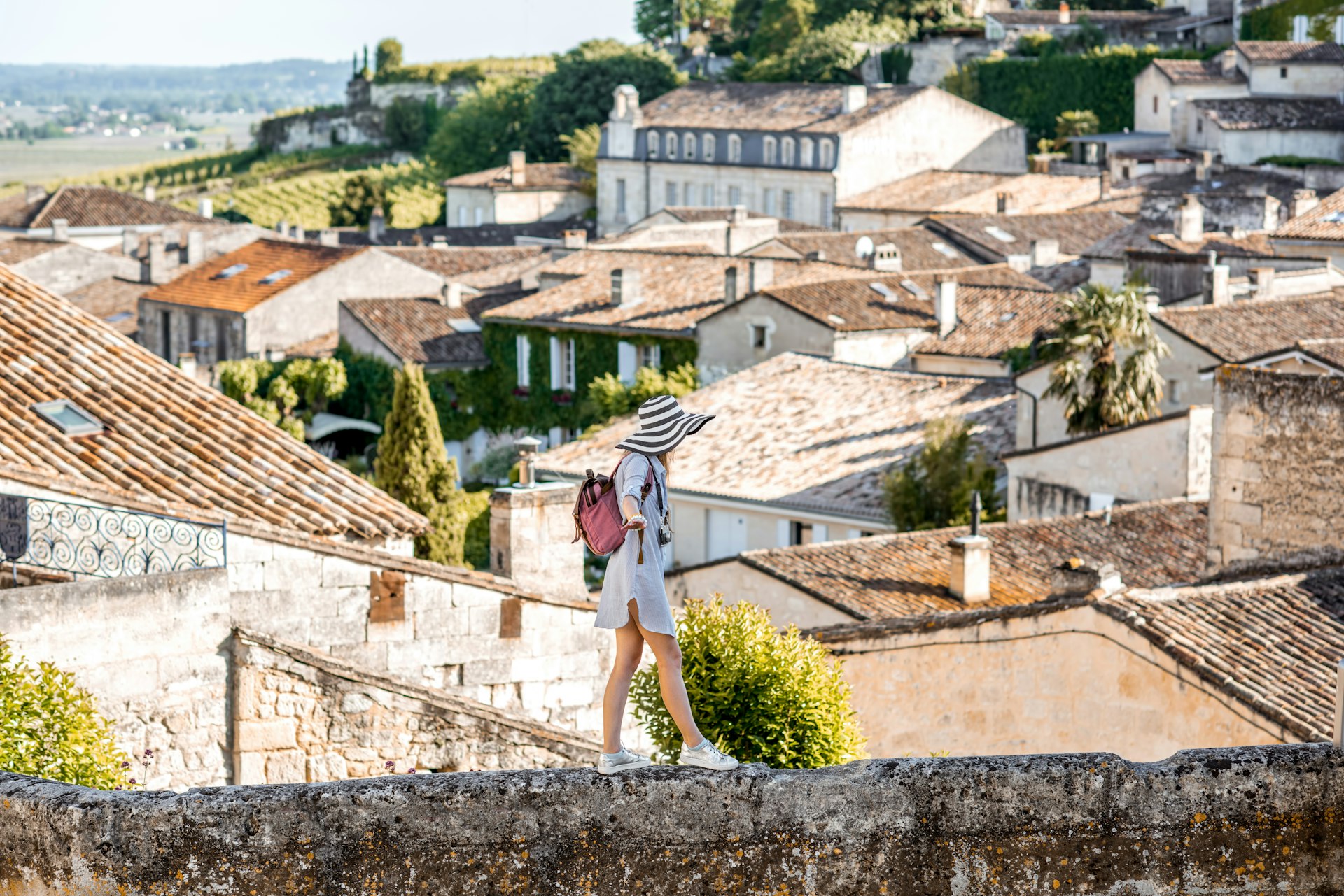 A woman walks carefully along a wall in the village of Saint Emilion in France