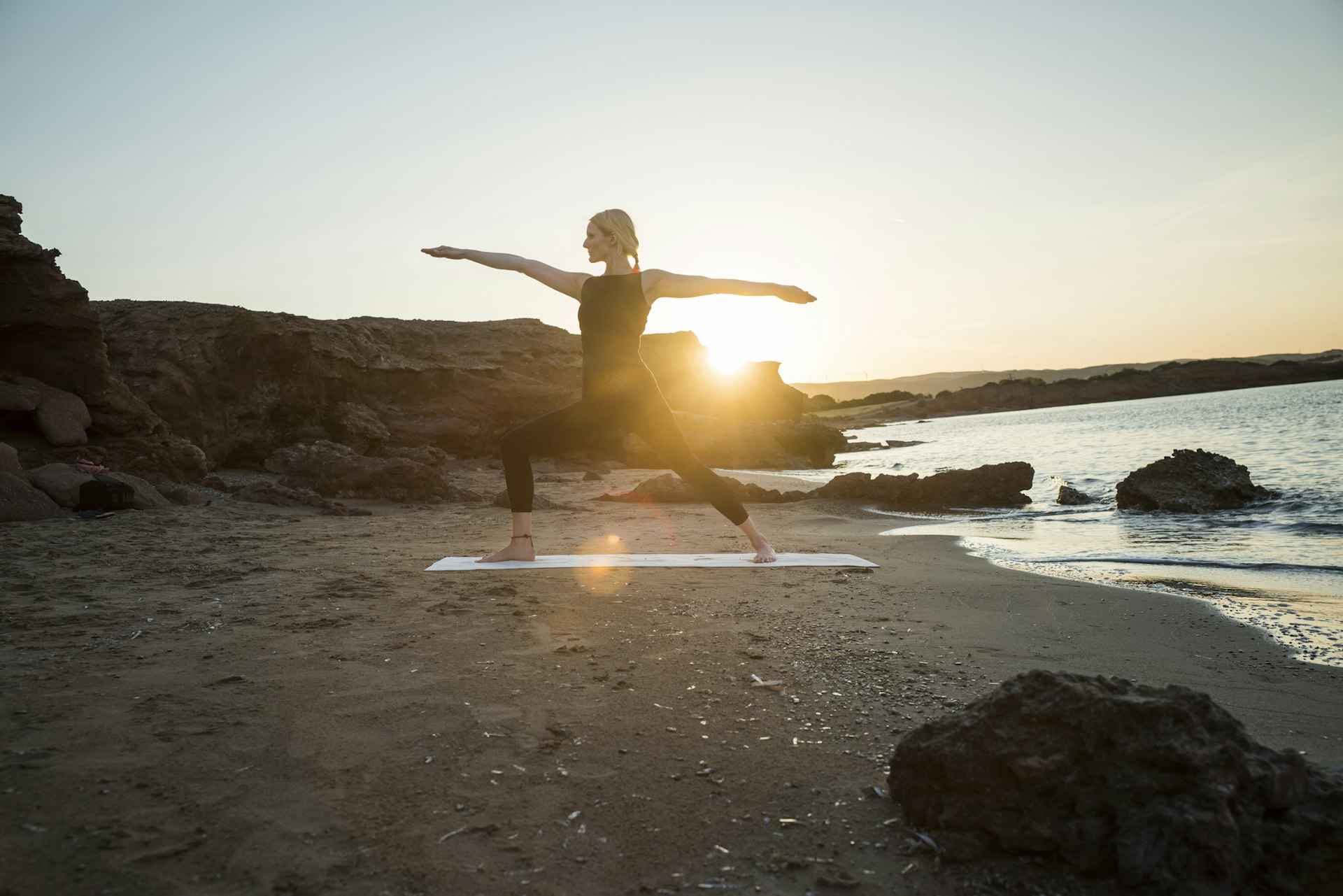Greece, Crete, woman practicing yoga on the beach at sunset