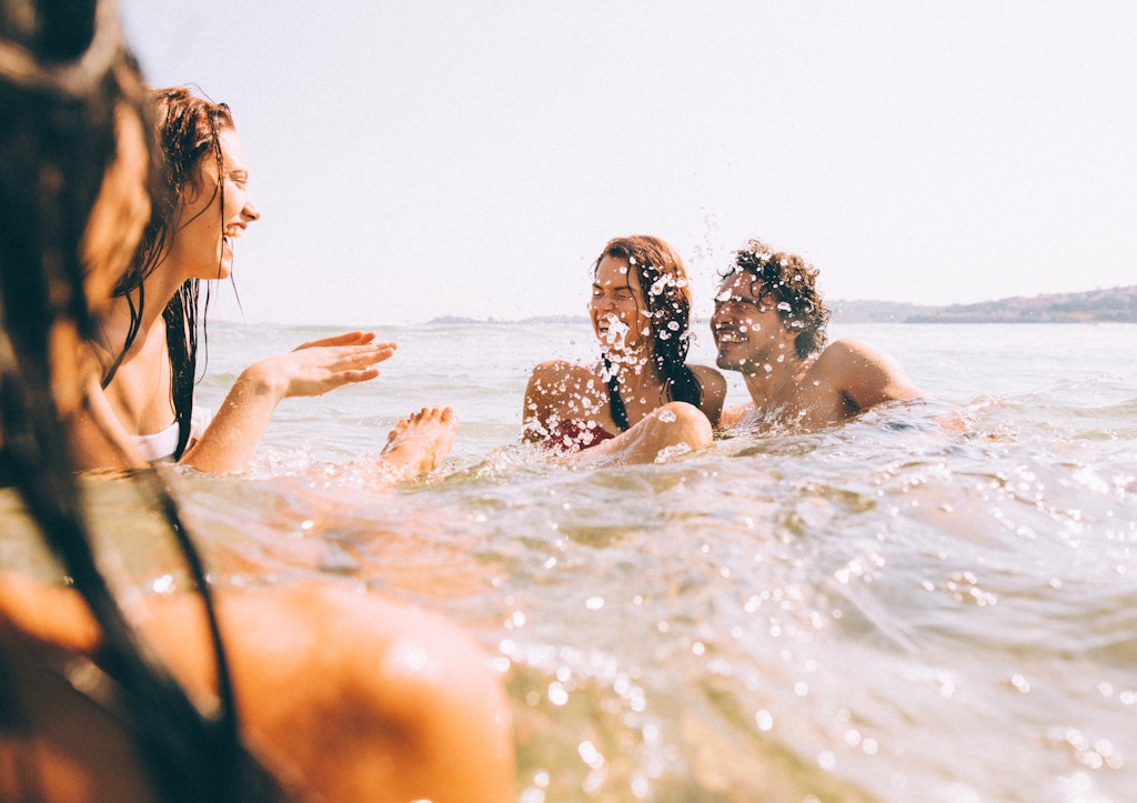 Four friends splashing each other with water in the sea.