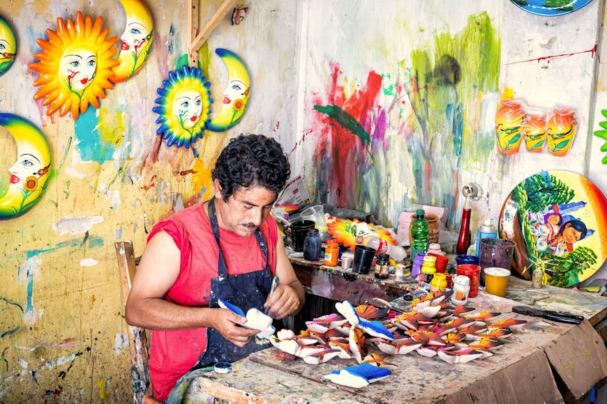 An artisan paints ceramic figures in the popular market of Tonala