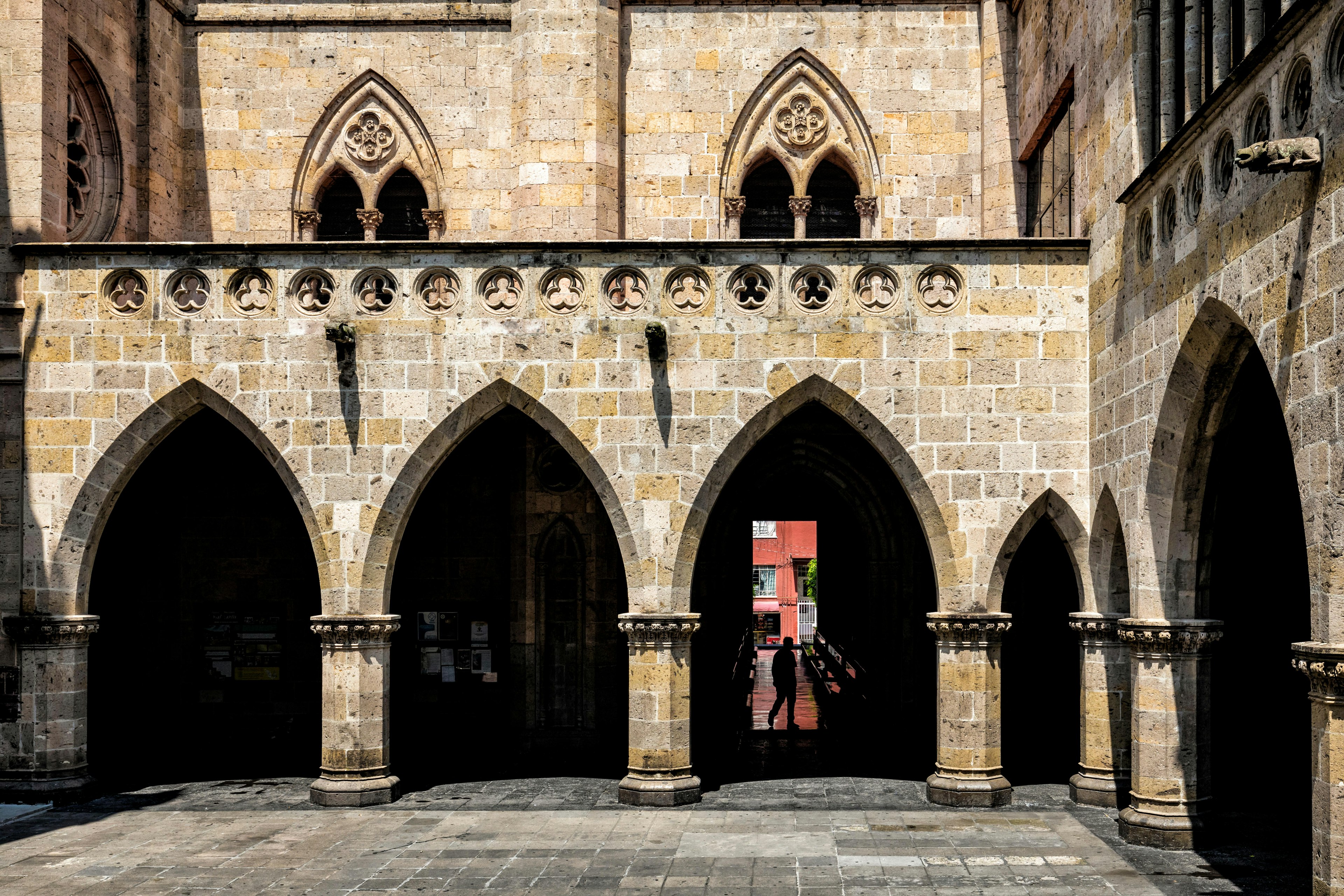 A silhouetted figure walks under the archway of a temple building in Guadalajara