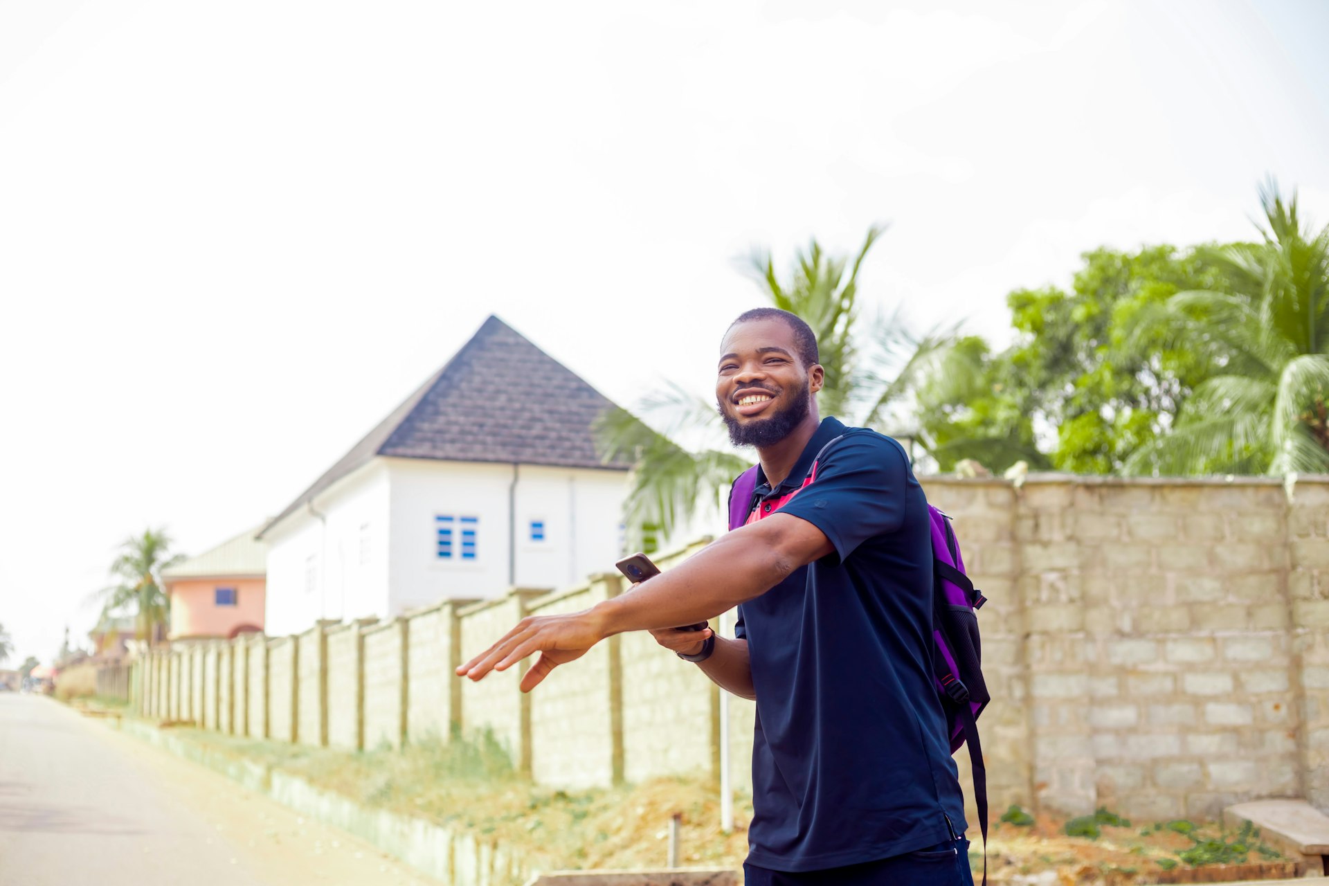 A young man hails a taxi or rideshare service in Nigeria, Africa