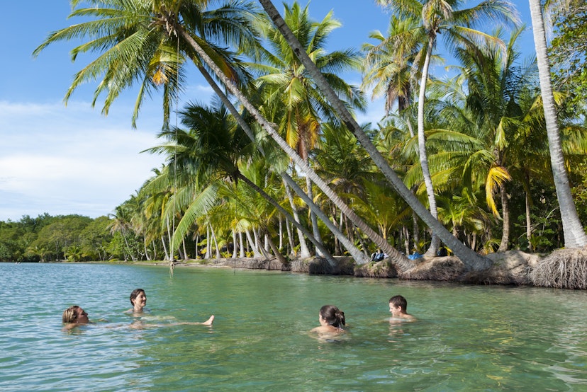 Four travelers from the United States, a young man and three women, enjoying the tranquil waters at Boca del Drago in Bocas del Toro, Panama