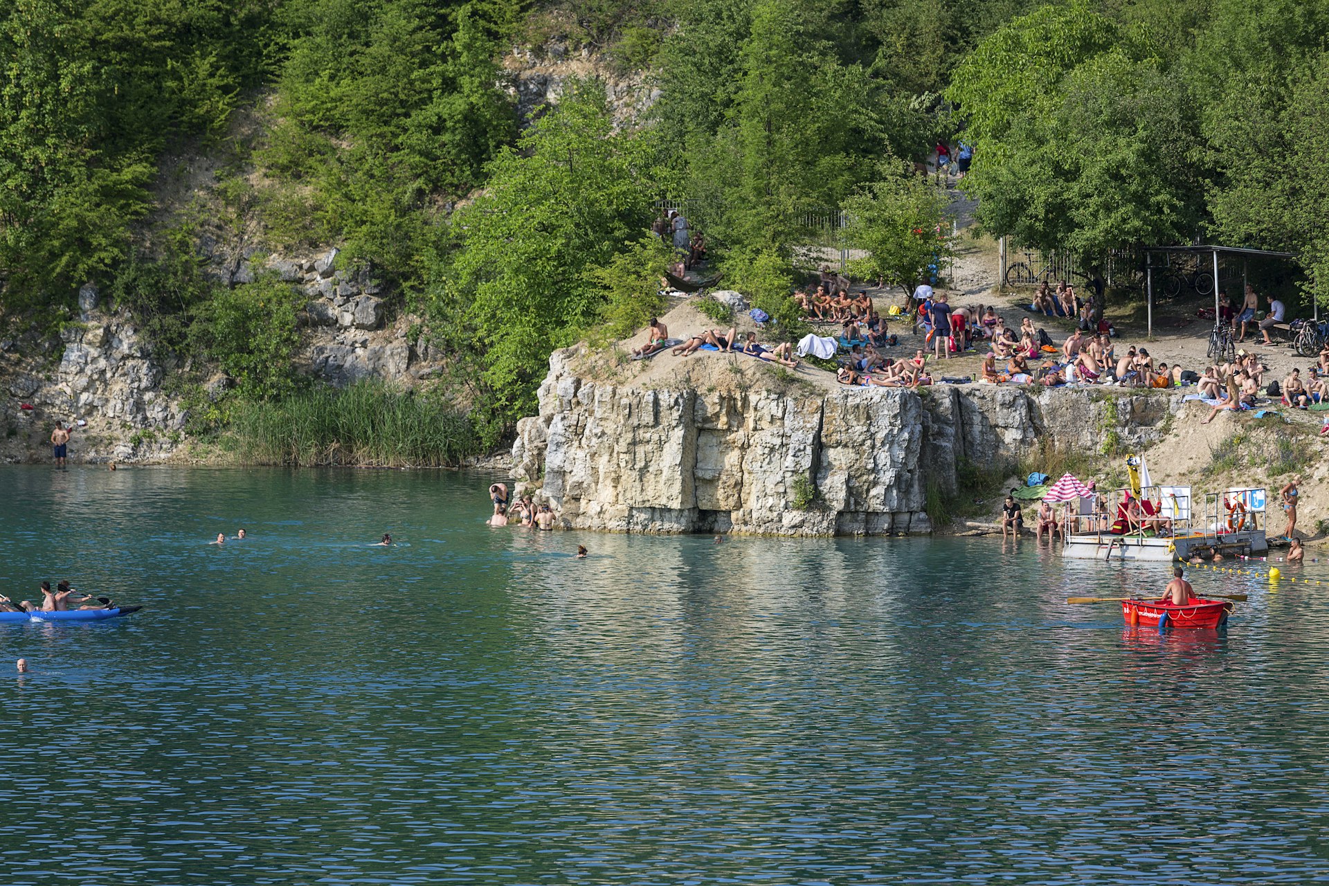 People relax around the edges of a lagoon with some swimmers in it