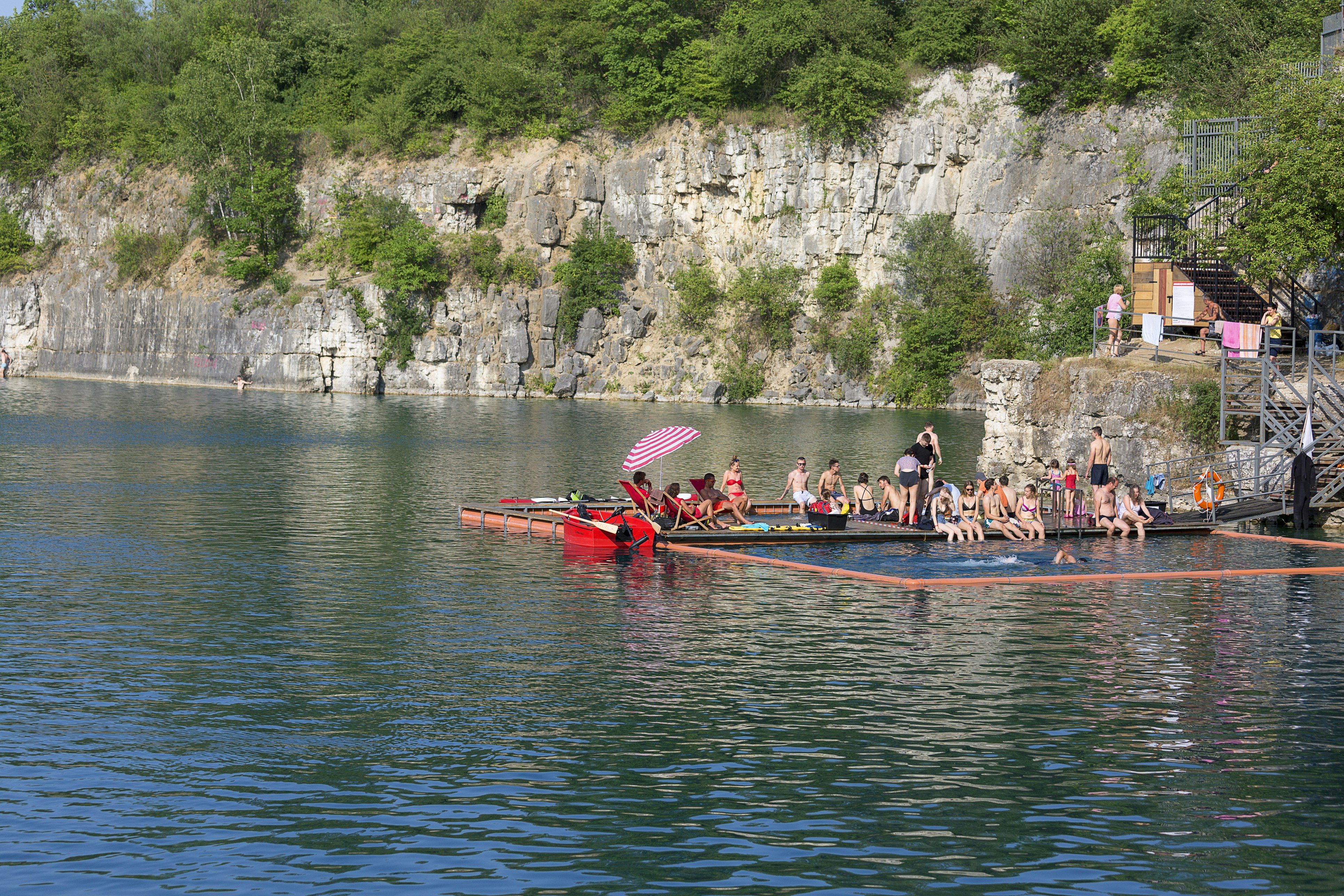 People rest on the pontoon of a lake in an old limestone quarry