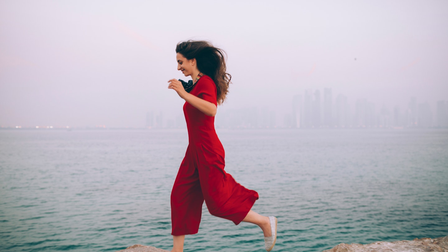 Woman Jumping Over The Rocks In Foggy Morning At The Seaside