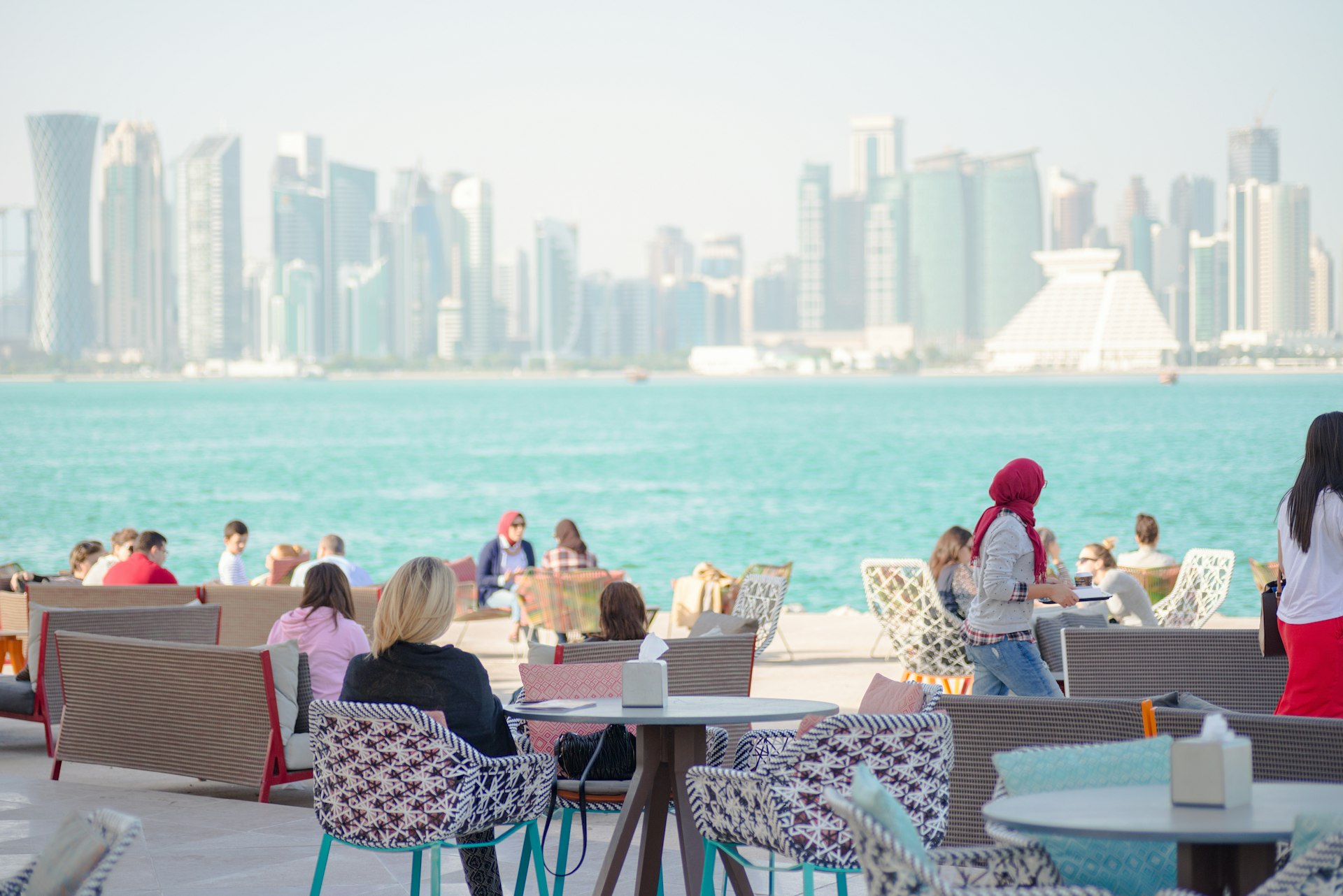 People sitting at the MIA or Museum of Islamic Art park by the sea overlooking the city of Doha Qatar