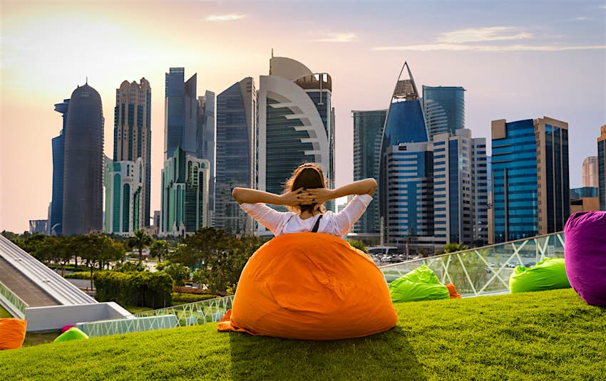 Woman sitting on a bean bag in a park and watching the skyline in Doha, Qatar; Shutterstock ID 611431022; your: Sloane Tucker; gl: 65050; netsuite: Online Editorial; full: Things to Know Qatar Article