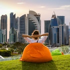 Woman sitting on a bean bag in a park and watching the skyline in Doha, Qatar; Shutterstock ID 611431022; your: Sloane Tucker; gl: 65050; netsuite: Online Editorial; full: Things to Know Qatar Article