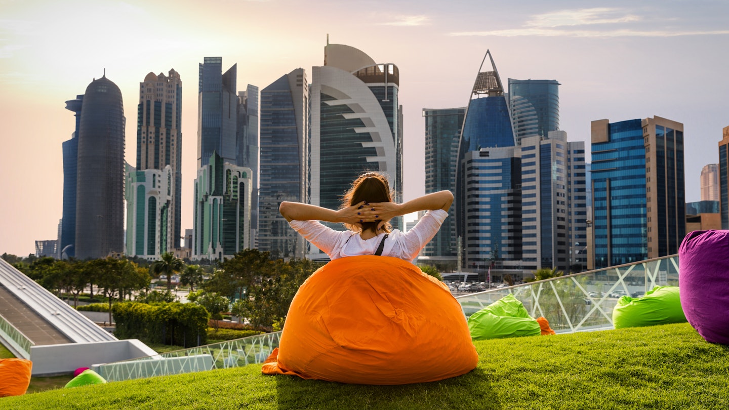 Woman sitting on a bean bag in a park and watching the skyline in Doha, Qatar; Shutterstock ID 611431022; your: Sloane Tucker; gl: 65050; netsuite: Online Editorial; full: Things to Know Qatar Article