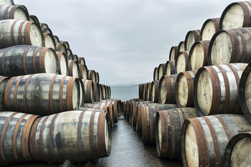 Två stora travar med whiskyfat sitter utanför Bunnahabhain-destilleriet, Isle of Islay, och väntar på att fyllas med whisky och förvaras
