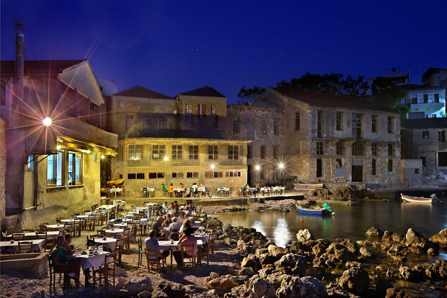 A wide view of diners on a waterfront terrace at night in Tabakaria, Chania, Crete, Greece, Mediterranean Sea