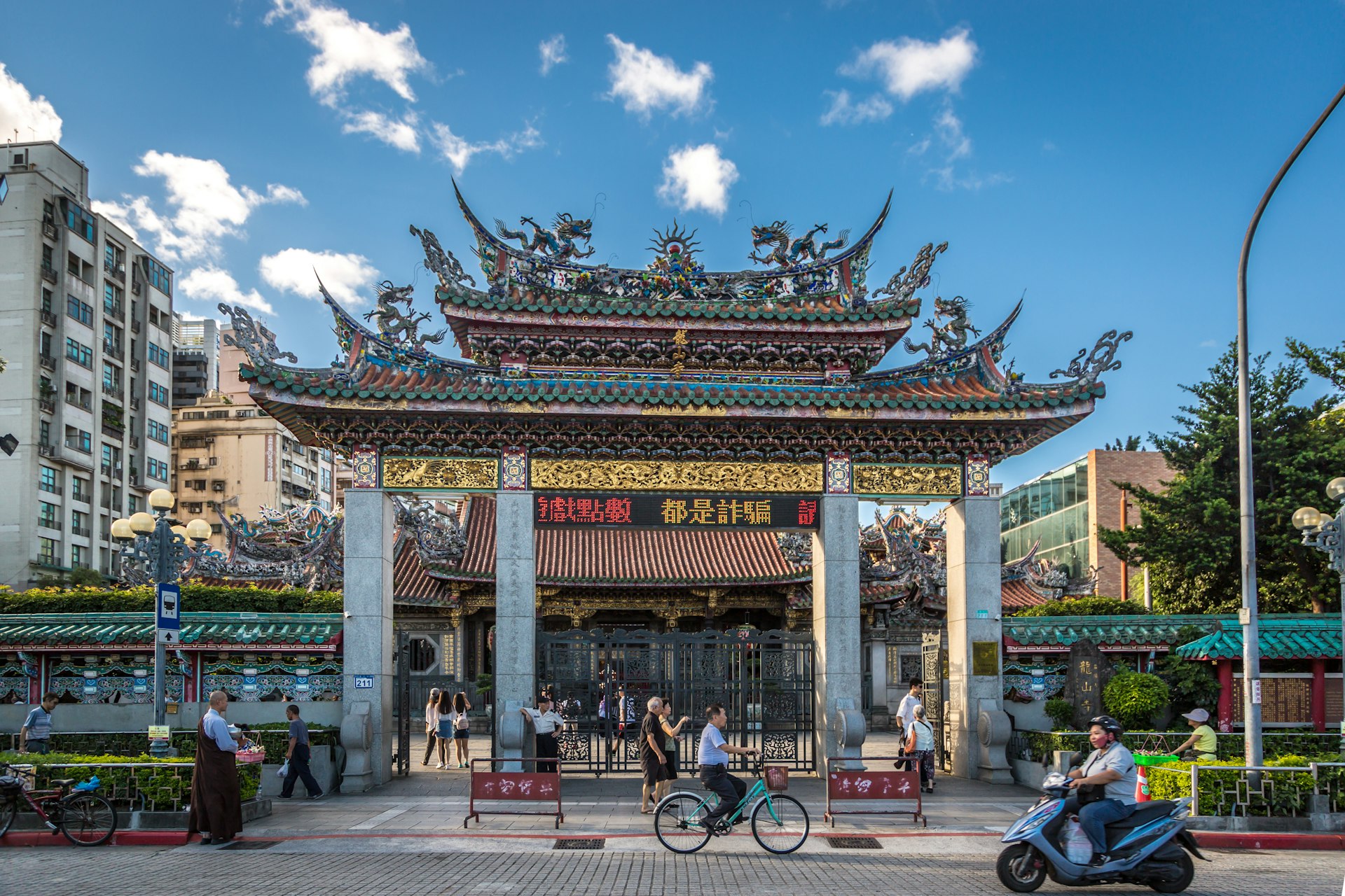 A cyclist pedals past the ornate gate of Longshan Temple, Taipei, Taiwan