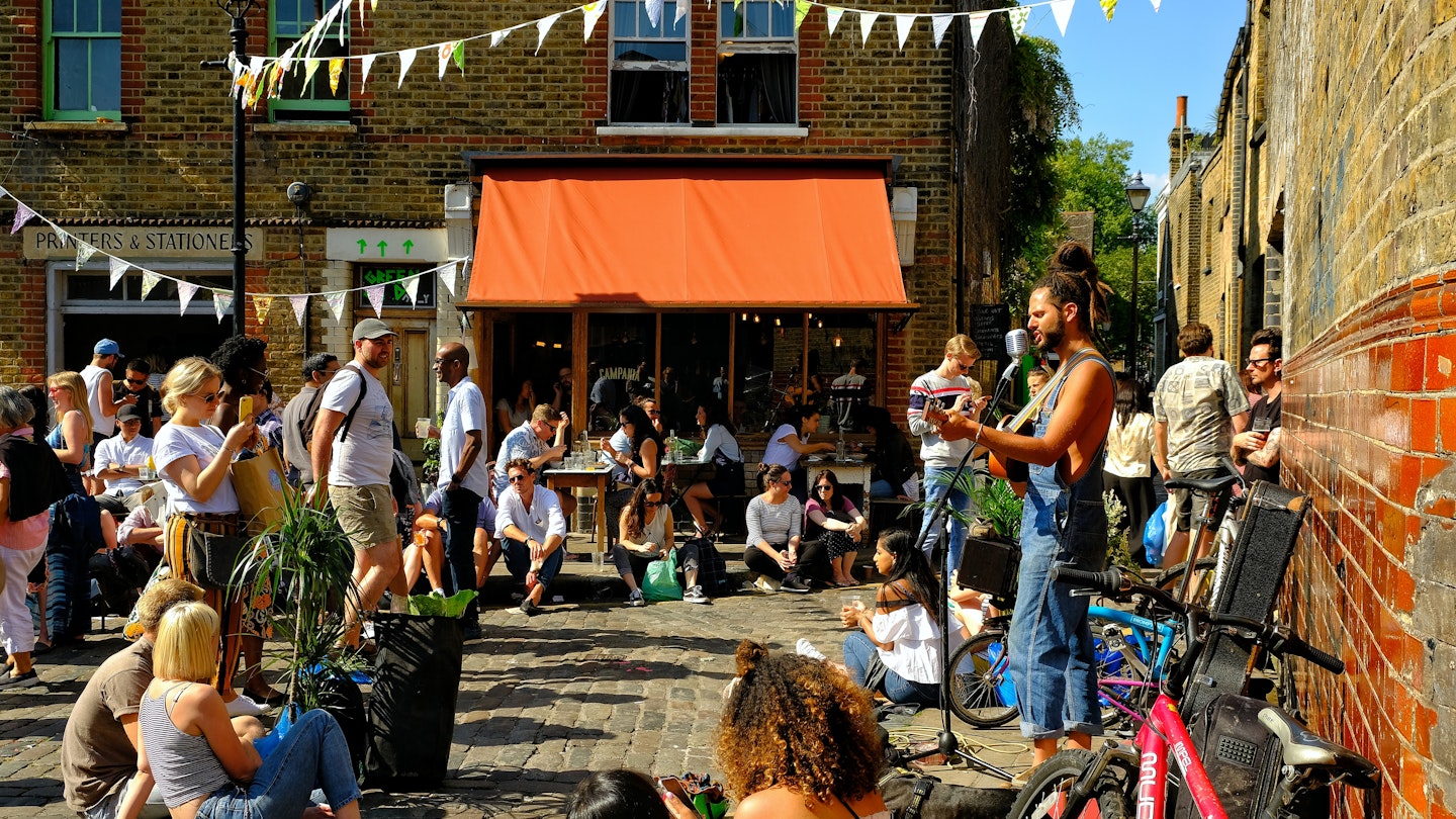 London, Great Britain: Young people having fun drinking and listening to street musicians in Hackney, East London on a sunny day