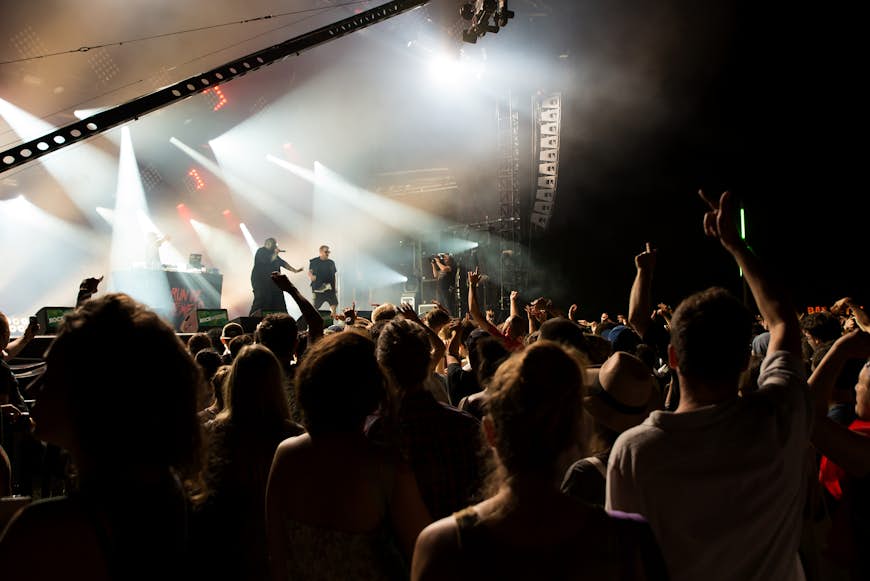 A crowd at a rock concert with the performers silhouetted against the stage lights