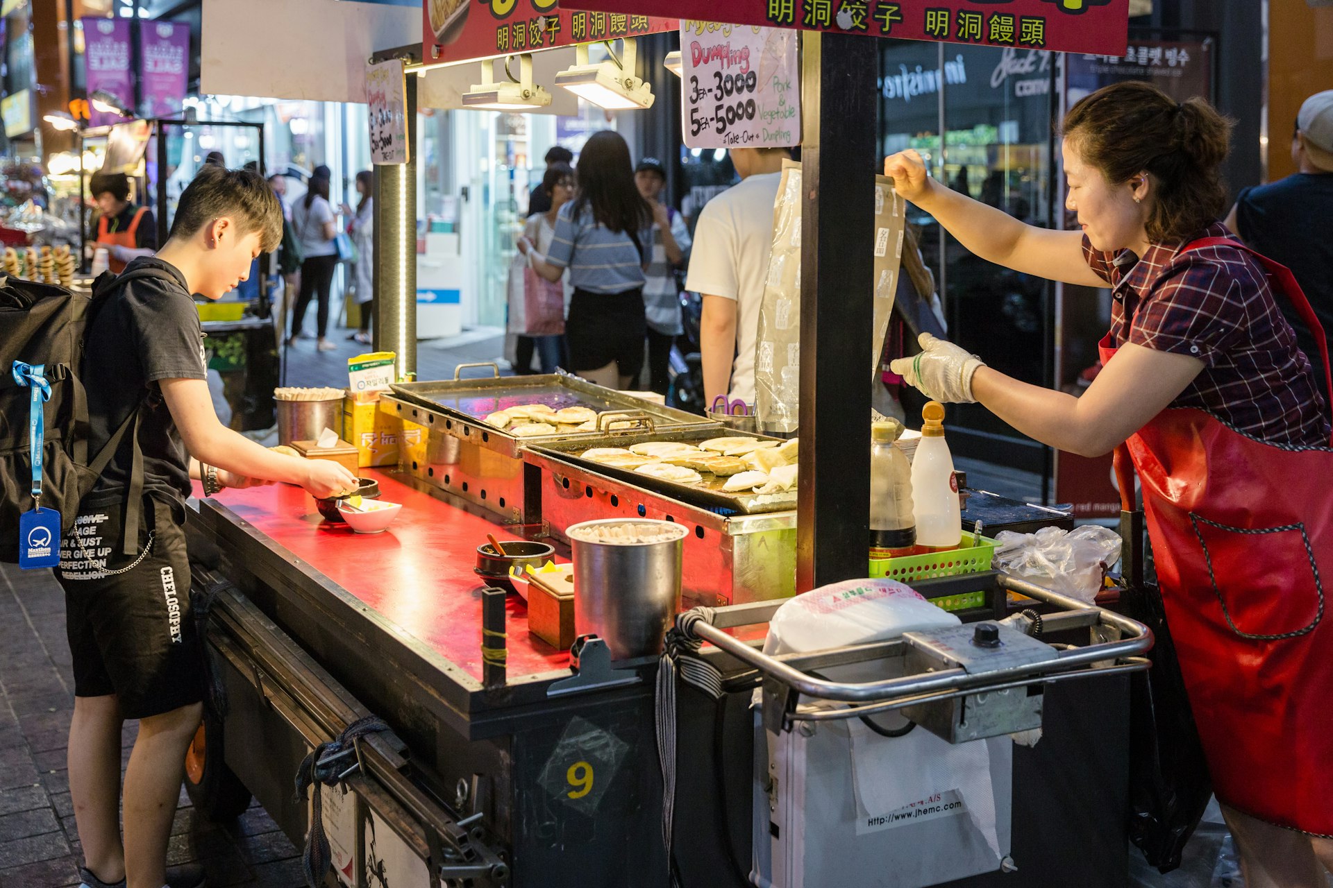 Crowds enjoy the Myeong-Dong district at night. The district is known as one of the main shopping and tourism areas. Myeongdong is a asian famous shopping for street food and fashion.