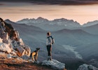 Woman hiking and looking at the view on the top of a mountain with a beautiful landscape at sunrise.
