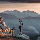 Woman hiking and looking at the view on the top of a mountain with a beautiful landscape at sunrise.