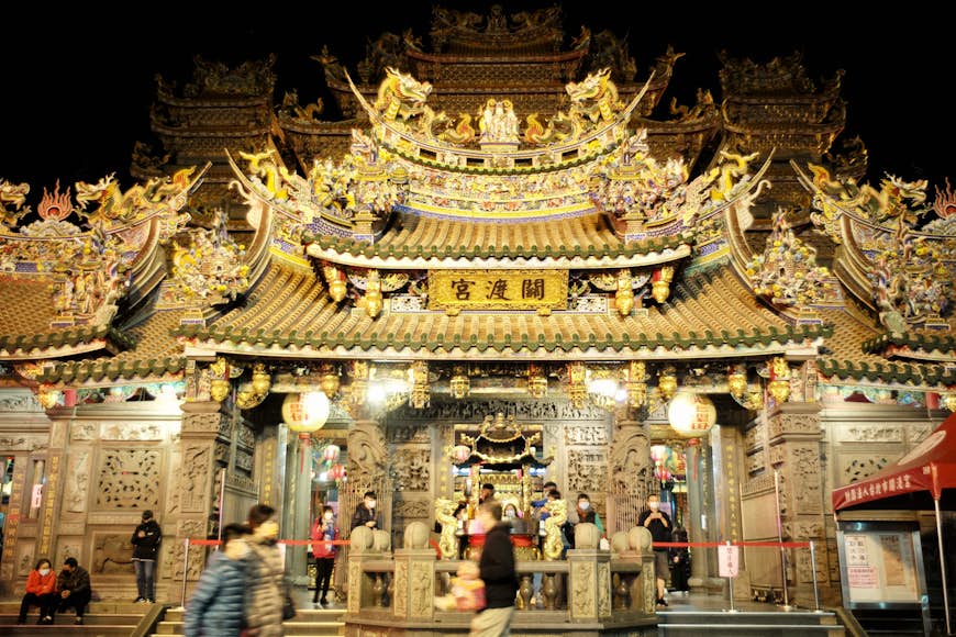 Local residents walk past the golden Guandu Temple on the eve of Lunar New Year, Taipei, Taiwan