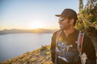 TTNK3J Smiling hiker standing on mountain at Crater Lake National Park during sunset