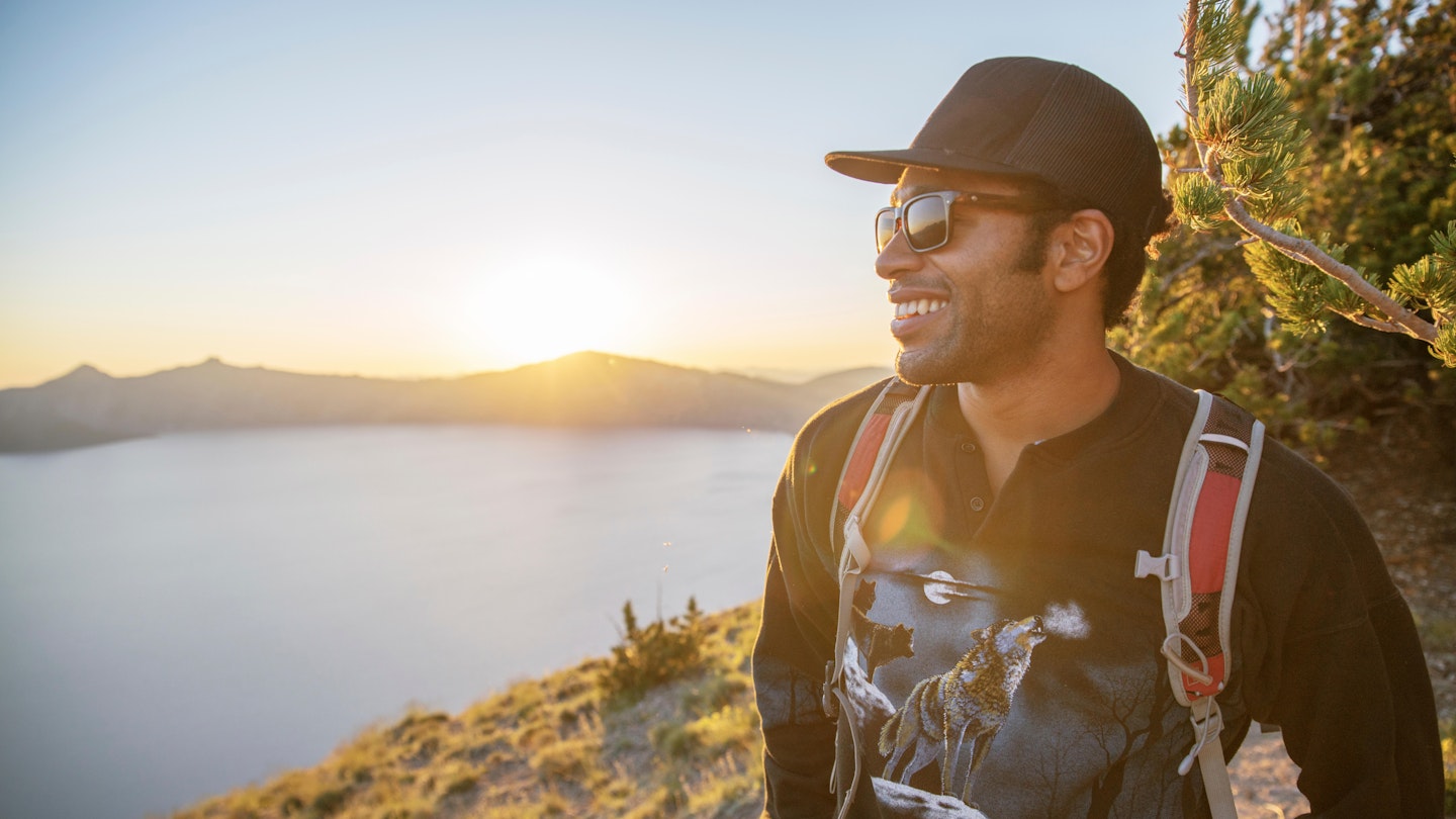 TTNK3J Smiling hiker standing on mountain at Crater Lake National Park during sunset